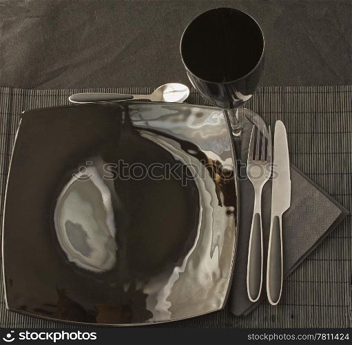 Black elegant plate and cutlery over black mat