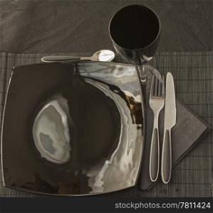 Black elegant plate and cutlery over black mat