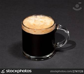 Black expresso coffee with heady froth in a glass mug or cup