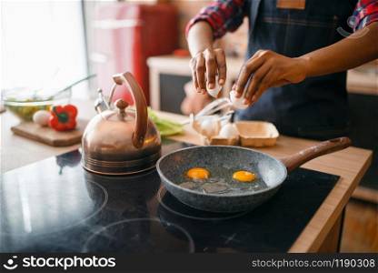 Black female person cooking fried eggs on the kitchen. African woman preparing breakfast at home. Healthy vegetarian lifestyle. Black female person cooking fried eggs on kitchen