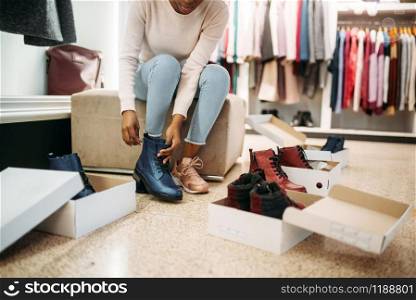 Black female person trying on shoes, shopping. Shopaholic in clothing store, consumerism lifestyle, fashion. Black female person trying on shoes, shopping