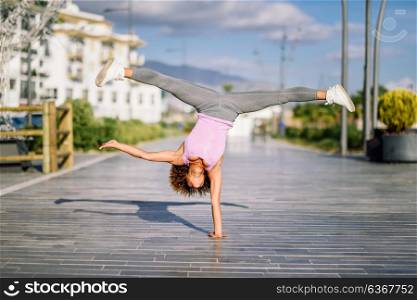 Black fit woman doing fitness acrobatics in urban background. Young female exercising and working out hard.