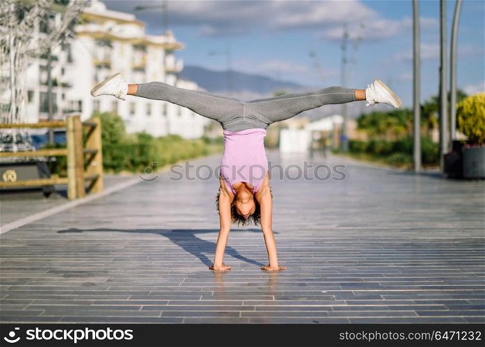 Black fit woman doing fitness acrobatics in urban background. Black fit woman doing fitness acrobatics in urban background. Young female exercising and working out hard.