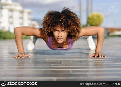 Black fit woman doing pushups on urban floor. Young female working out in the street.