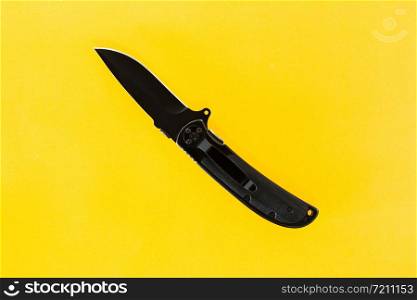 black folding knife on a yellow background.