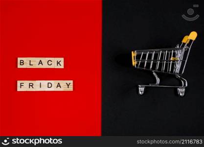 Black Friday sale concept. Mini shopping cart and sign on a red background. Banner for advertising.. Black Friday sale concept. Mini shopping cart and sign on red background. Banner for advertising.