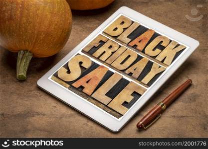 Black Friday sale - holiday shopping concept -word abstract in letterpress wood type on a digital tablet with pumpkins