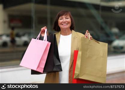 Black friday. Smiling adult woman with shopping bags. Middle ages female after shopping on shopping mall background. Purchases, discounts, sale concept. Online shopping concept, Seasonal Sales.mockup. Black friday. Smiling adult woman with shopping bags. Middle ages female after shopping on shopping mall background. Purchases, discounts, sale concept. Online shopping concept, Seasonal Sales. mockup