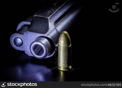 Black gun and bullets on a black background.
