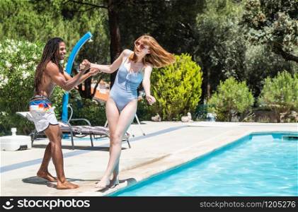 black guy with dreadlocks playing in a pool with caucasian girl.