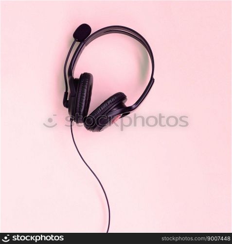 Black headphones lies on a colorful pastel pink background. Music listening concept. Flat lay top view. Music listening concept. Black headphones lies on pink background
