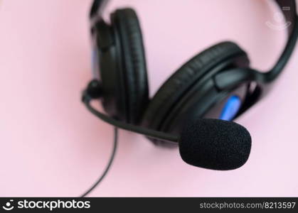 Black headphones lies on a colorful pastel pink background. Music listening concept. Music listening concept. Black headphones lies on pink background