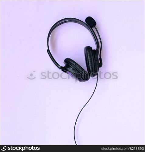 Black headphones lies on a colorful pastel violet background. Music listening concept. Flat lay top view. Music listening concept. Black headphones lies on violet background