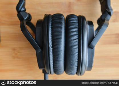 Black headphones on wooden background.. Black big headphones monitor on wooden background