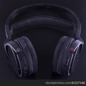 Black headphones over black background, square image