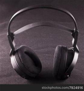 Black headphones over black tissue background, square image