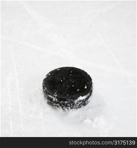 Black hockey puck on ice rink.