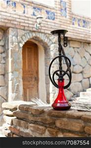 Black hookah with ruby bulb in authentic oriental antique cafe, outdoor. Front view, full length. Vertical.