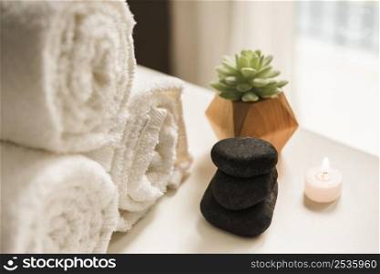 black hot stone lighted candle cactus plant rolled up white towel