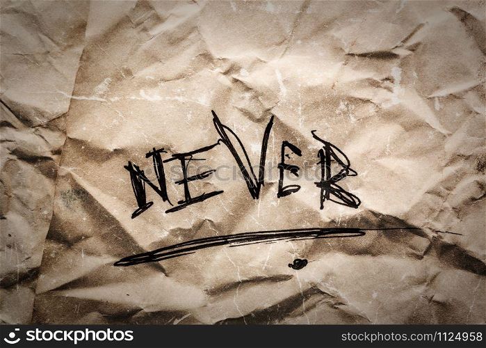 "Black inscription "Never" on an old piece of paper"