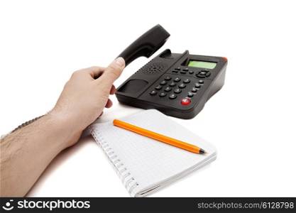 Black IP phone, notebook and pen on white background
