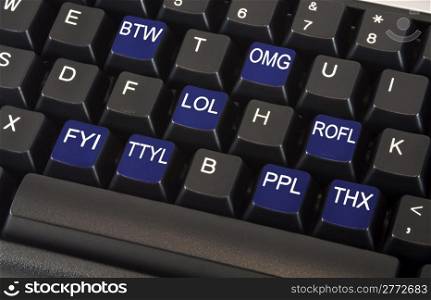 Black keyboard with text message slang words on keys including LOL, OMG, BTW, ROFL, FYI, TTYL, PPL and THX to illustrate fast paced social networking lifestyle concept.