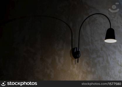 Black lamp on grunge concrete cement wall in loft style. Selective focus.
