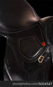 Black leather professional saddle at black background