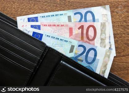 black leather wallet with euros on the table