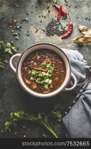 Black lentil soup in soup bowl on dark table background with spoon. Healthy vegetarian or vegan food concept. Top view