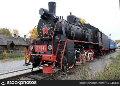 Black locomotive and blue car on the railway station in Medvezshyegorsk, Karelia, Russia