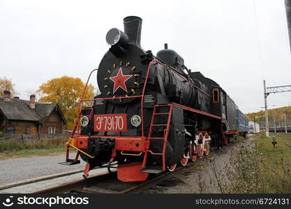 Black locomotive and blue car on the railway station in Medvezshyegorsk, Karelia, Russia