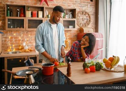 Black love couple cooking romantic dinner on the kitchen. African family preparing vegetable salad at home. Healthy vegetarian lifestyle