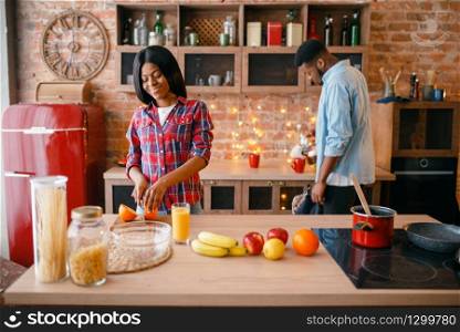 Black love couple cooking romantic dinner on the kitchen. African family preparing vegetable salad at home. Black love couple cooking romantic dinner