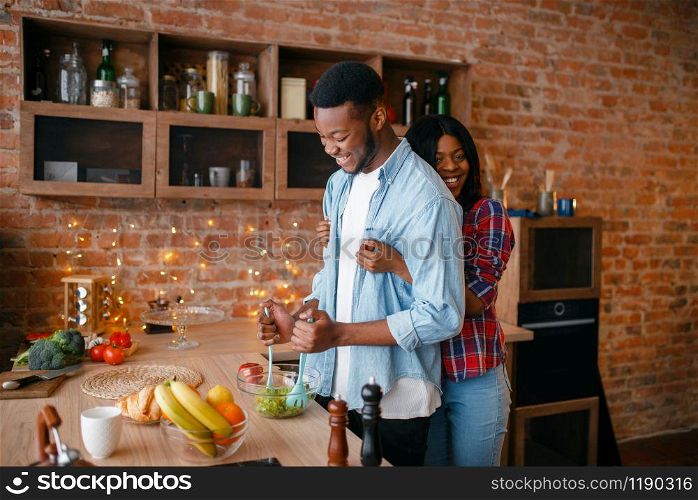 Black man cooking breakfast on the kitchen. African couple preparing vegetable salad at home. Healthy vegetarian lifestyle