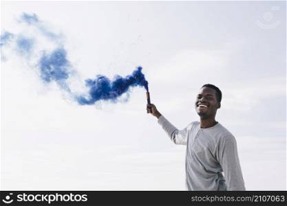 black man holding blue smoke bombs