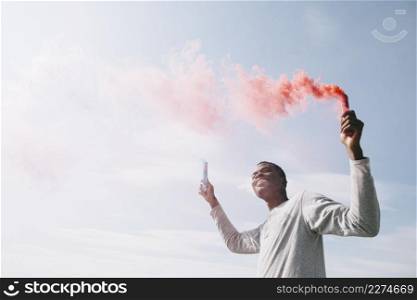 black man holding colored smoke bombs