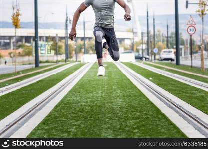 Black man jumping in urban background. Male doing workout in the street.