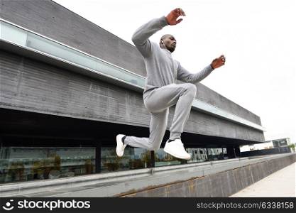 Black man jumping in urban background. Male doing workout outdoors.