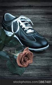 black man&rsquo;s shoe and rose on wooden background