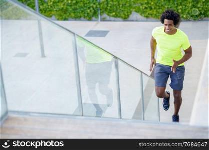 Black man running upstairs outdoors. Young male exercising in urban background.. Black man running upstairs outdoors. Young male exercising.