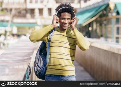 Black man with afro hair listening to music with wireless headphones sightseeing in Granada, Andalusia, Spain.. Black man listening to music with wireless headphones sightseeing in Granada