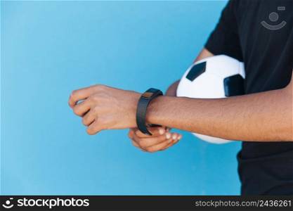 black man with football fixing smart watch