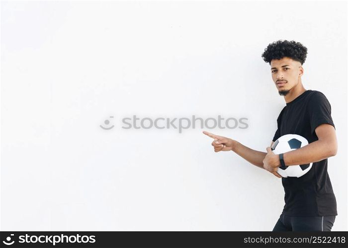 black man with soccer ball pointing with finger