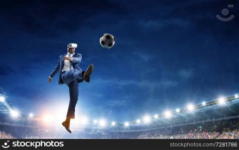 black man with virtual reality helmet playing soccer on night stadium with burning lights. Black businessman on virtual reality football match