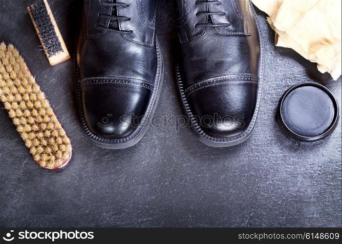 black men&rsquo;s shoes with care accessories on a dark background