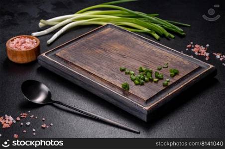Black metal spoon and rectangular cutting board on black concrete background. Preparing for Cooking. Black metal spoon and rectangular cutting board on black concrete background