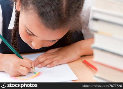Black mixed race biracial African American girl child schoolgirl in classroom drawing a rainbow
