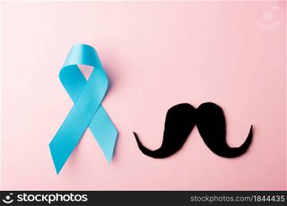 Black mustache paper and light blue ribbon, studio shot isolated on pink background, Prostate cancer awareness month, Fathers day, minimal November moustache concept