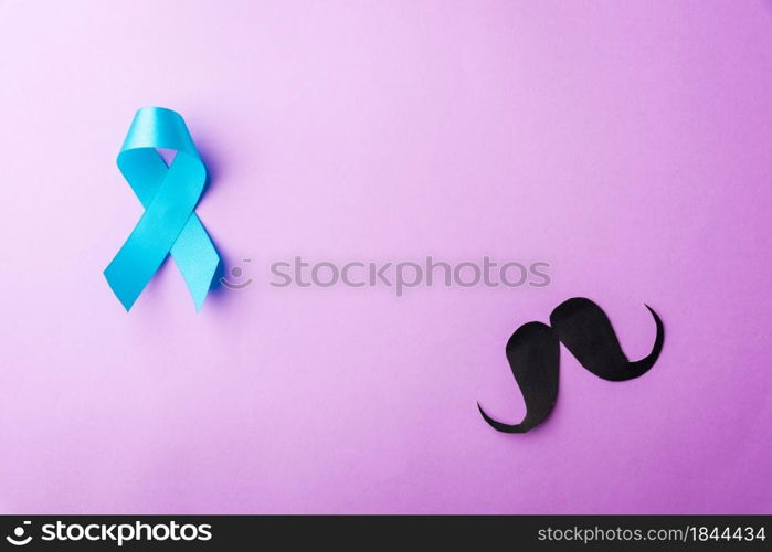 Black mustache paper and light blue ribbon, studio shot isolated on purple background, Prostate cancer awareness month, Fathers day, minimal November moustache concept